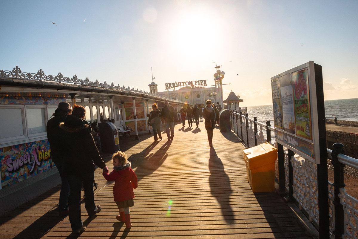 Visitors still enjoy walking along the lively promenade of Brighton Pier today, just as they did in the past