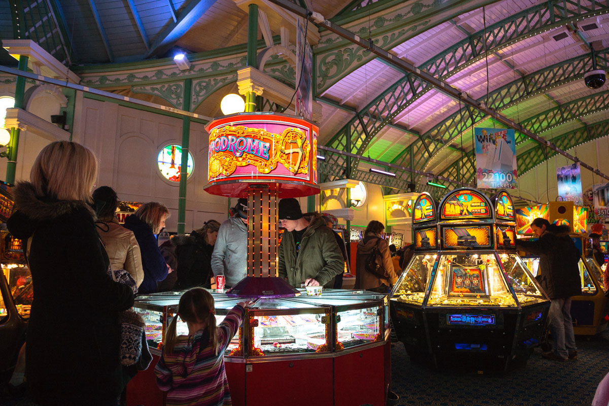 Brighton Pier arcades today, with colourful game machines, flashing lights, and visitors enjoying classic seaside fun