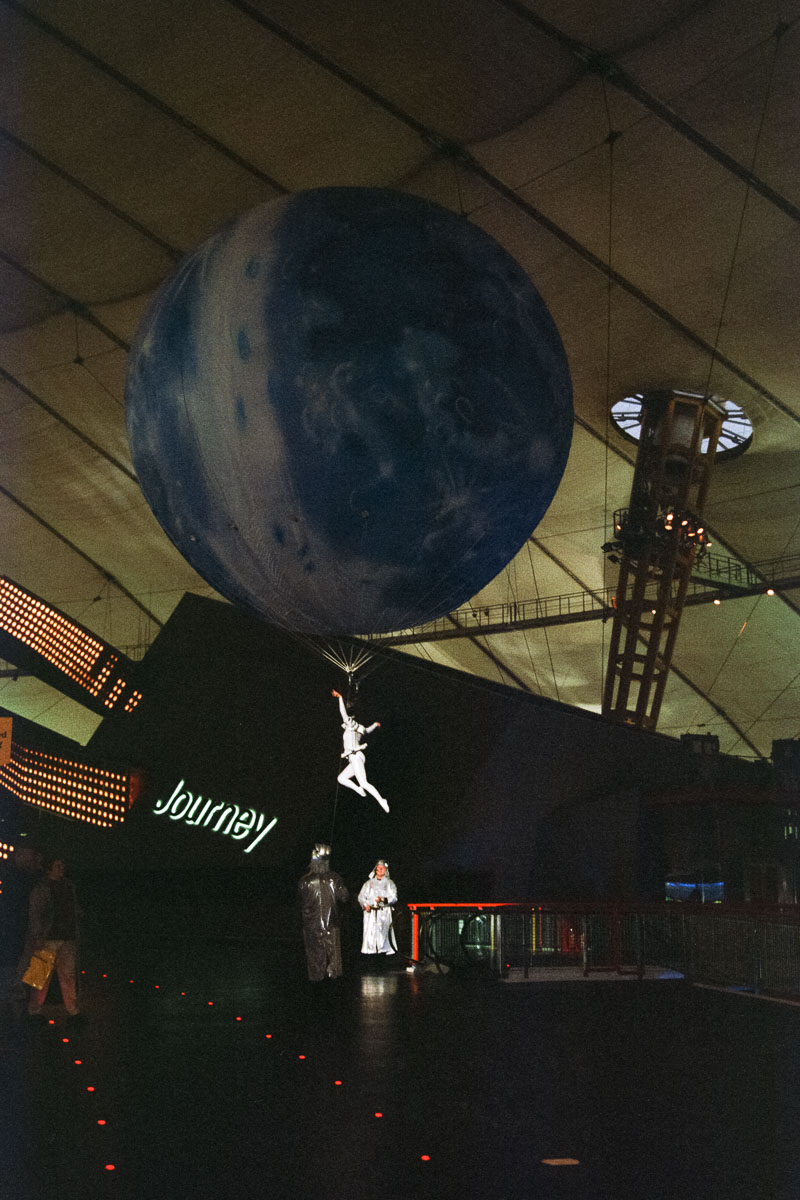 An acrobat, suspended by a large Earth-patterned balloon inside the Millennium Dome exhibition