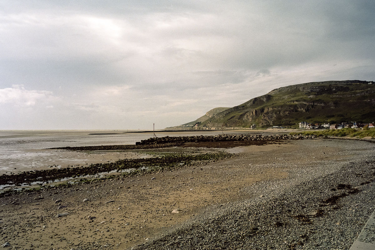 The pebbly beach stretches toward the Great Orme