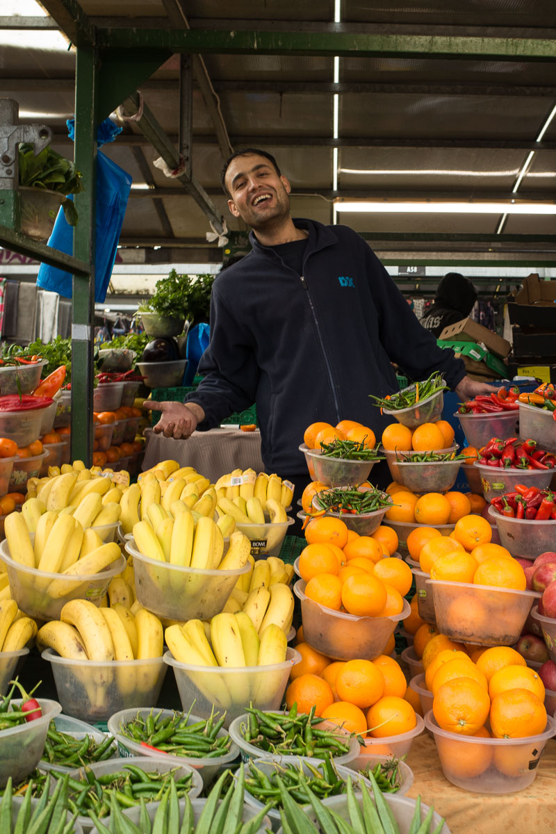 A jovial vendor poses among his colourful produce at Birmingham's Bullring Open Market.