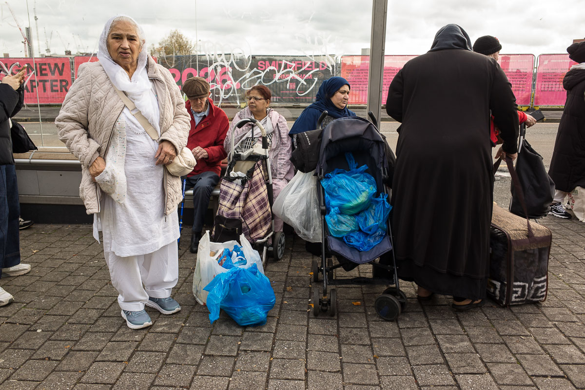 Shoppers rest at a bus stop outside Birmingham's Bullring Open Market—a perfect street photography moment.