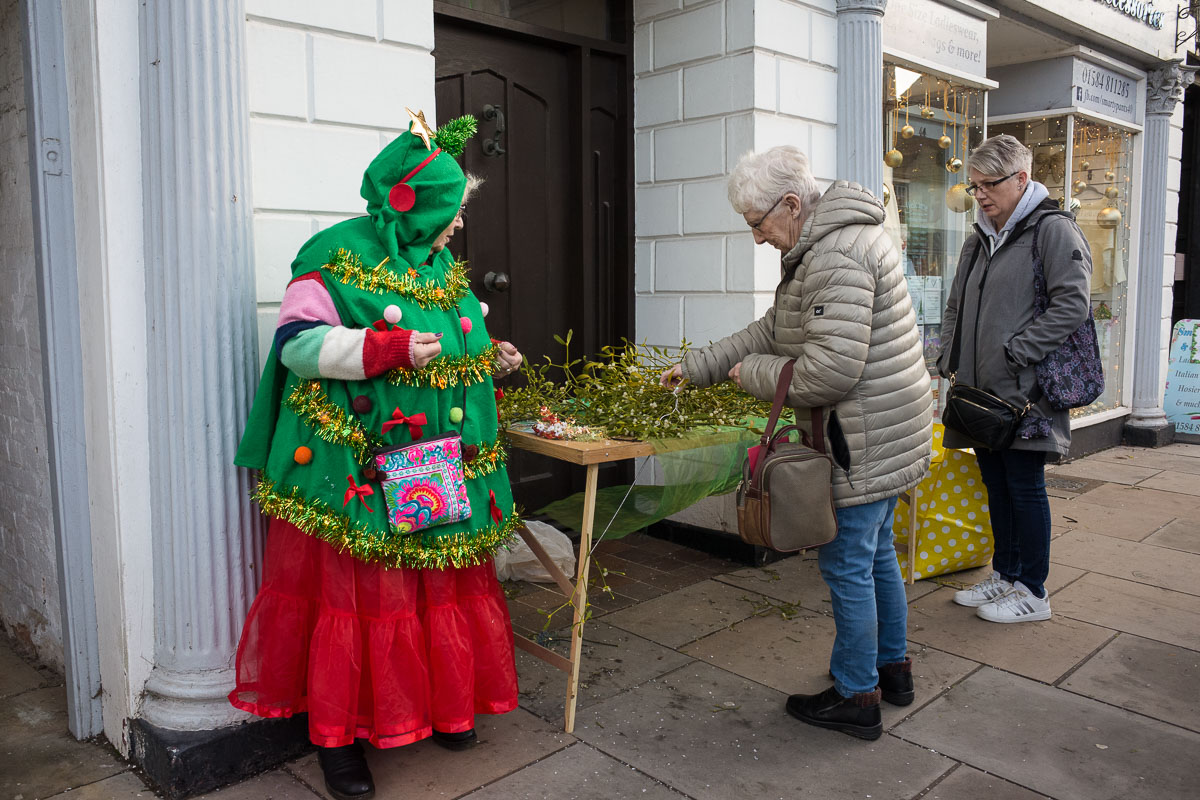 A woman dressed as a Christmas tree sells mistletoe at Tenbury Mistletoe Festival
