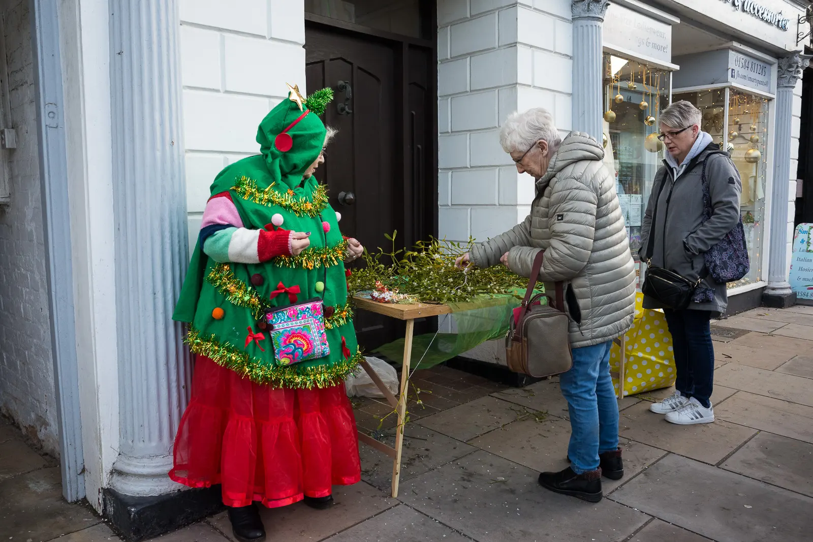 A woman dressed as a Christmas tree sells mistletoe at Tenbury Mistletoe Festival