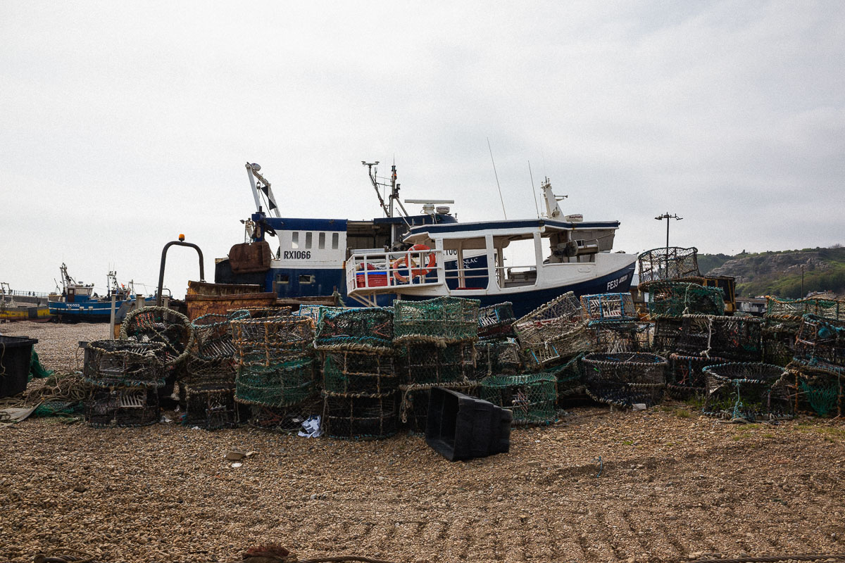 Fishing cages stacked on Hastings Beach, highlighting ongoing fishing activity and the town's maritime heritage