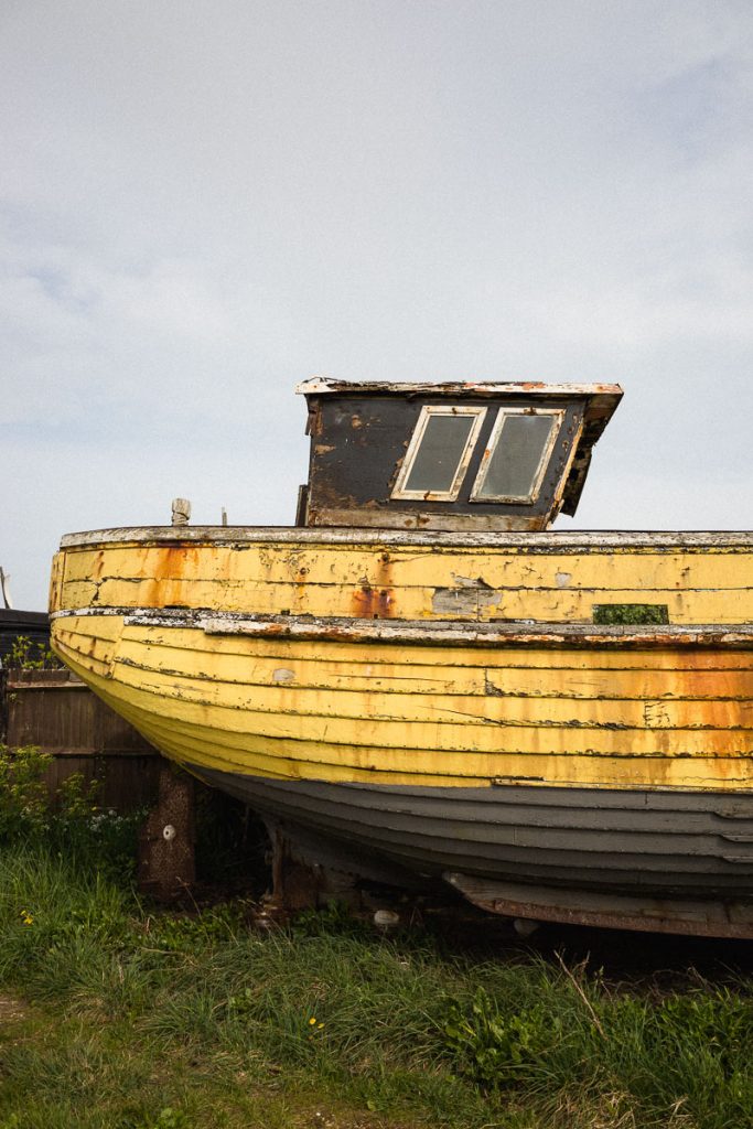 Peeling yellow paint on a weathered wooden fishing boat on Hastings Beach—ideal for urbex photography