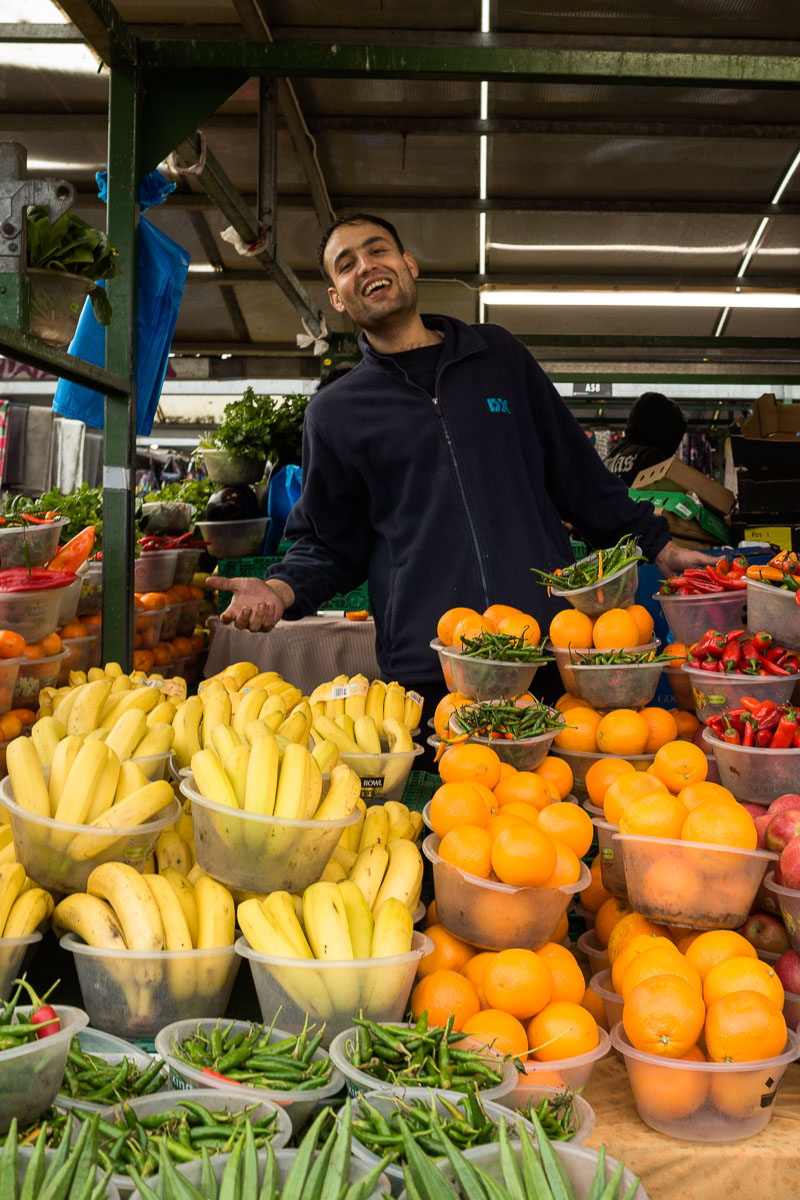 A cheerful vendor stands among his colourful fruit and vegetables at the Bullring Open Market