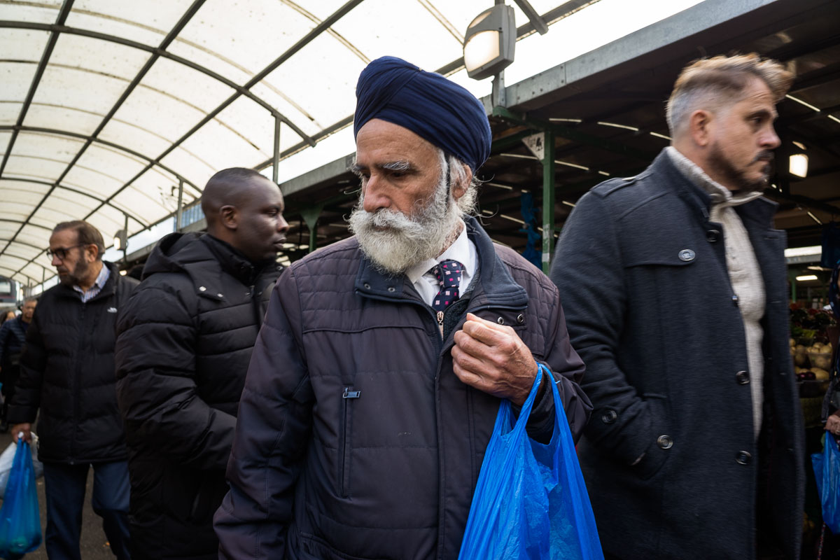A man carries a blue poly bag—an everyday essential for shopping at the market