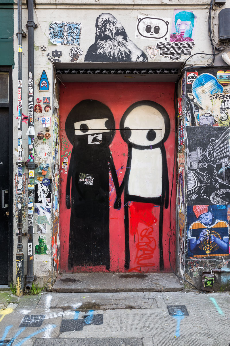 A Stik mural of a woman wearing a niqab holding hands with another figure