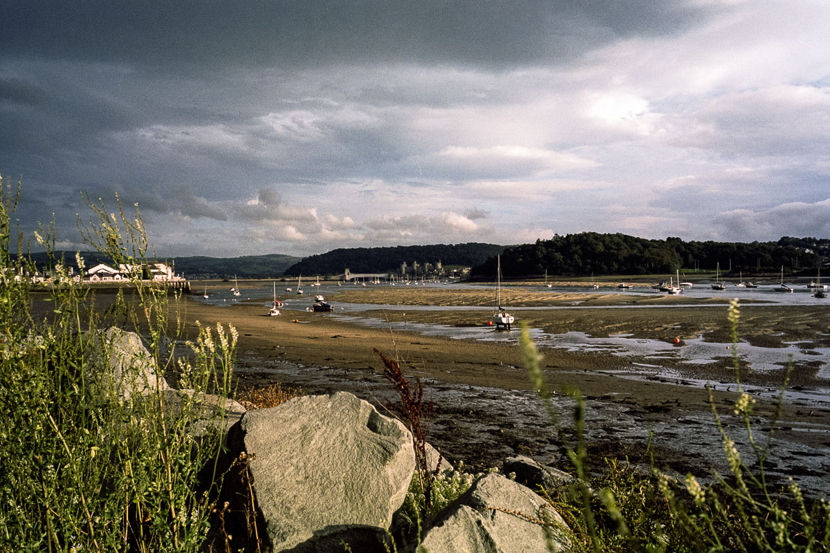 At low tide, you can follow the sandy shore toward the imposing Conwy Castle
