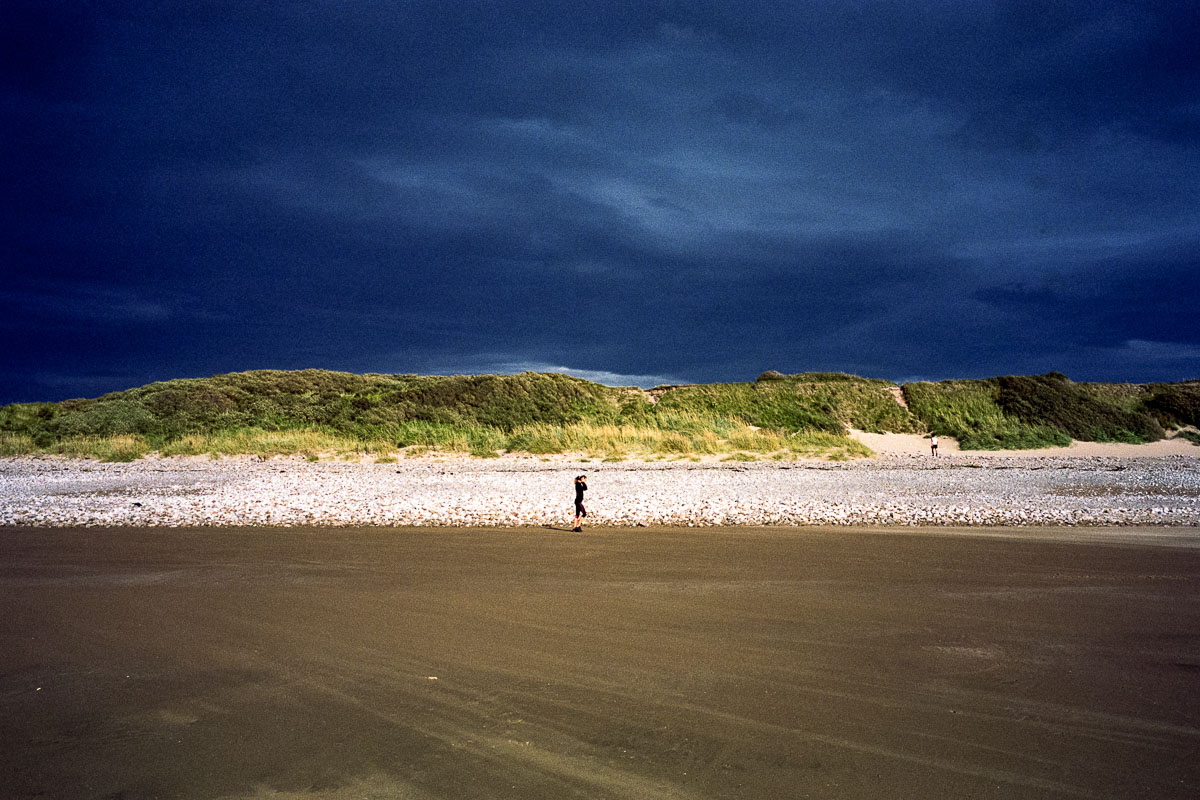 A lone jogger runs along Llandudno's West Shore Beach beneath an intense, cobalt sky