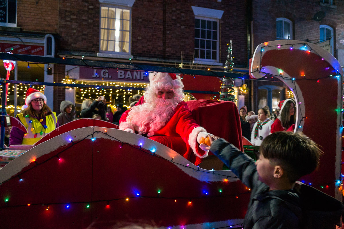 Santa hands out oranges to children as the parade passes by