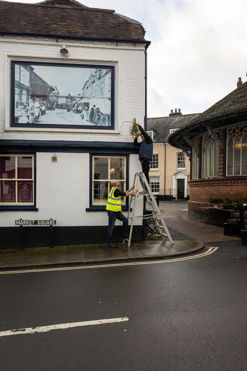 Locals hang mistletoe outside shops during the Tenbury Mistletoe Festival