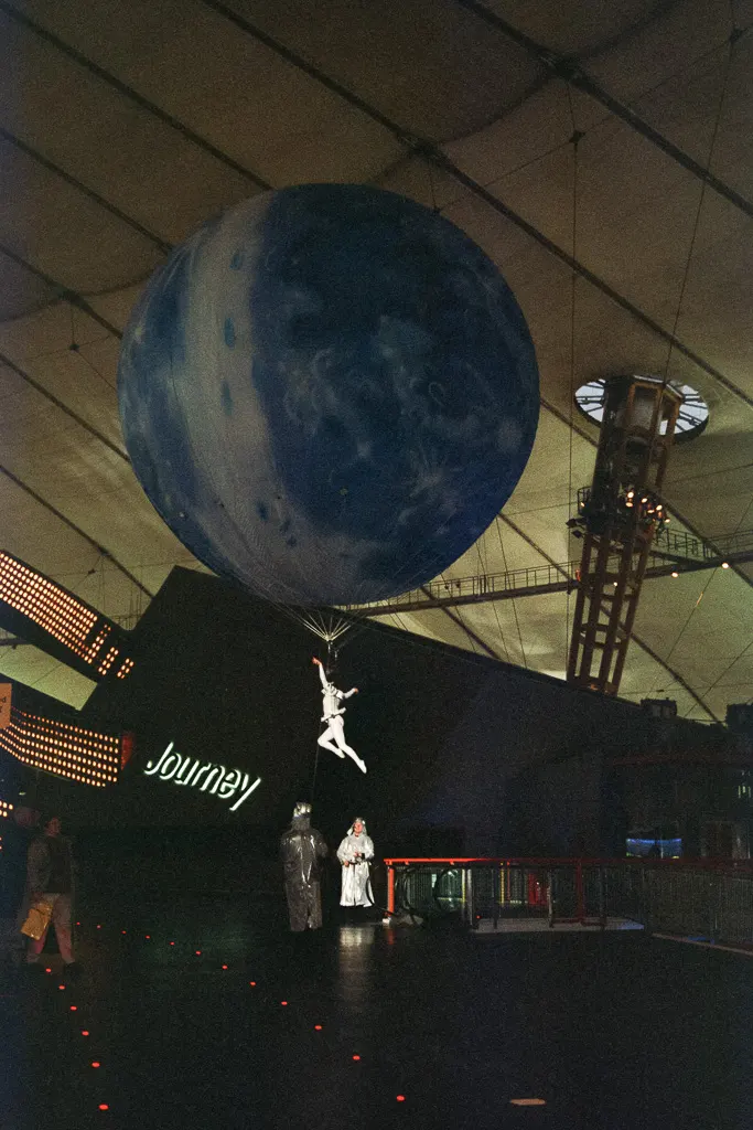 An acrobat, suspended by a large Earth-patterned balloon inside the Millennium Dome exhibition